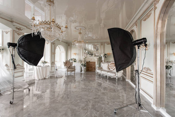 Innenraum eines Fotostudios. klassische luxuriöse Apartments mit weißem Kamin, Sofa, großen Fenstern und Kronleuchter. - Foto, Bild