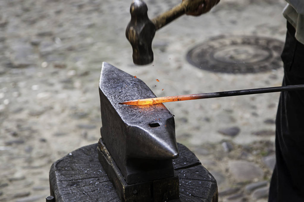Rotes heißes Eisen in einer Schmiede, Arbeit mit heißem Eisen, traditionelle Arbeit - Foto, Bild