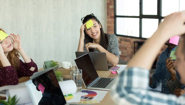 Young coworkers playing game with paper stickers on forehead - Photo, image