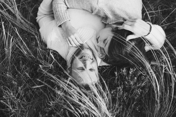 Felice giovane coppia amorevole sdraiato in erba piuma, ridendo e abbracciando, vista dall'alto. Stile bianco e nero
 - Foto, immagini