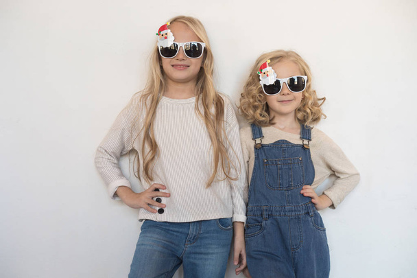 Two little girls in funny glasses in the form of Christmas trees. - Foto, imagen