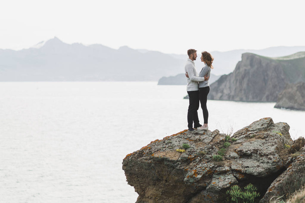 Молода пара ходить по скандинавському морському узбережжю з видом на гори навесні, повсякденний стиль одягу светри і джинси
 - Фото, зображення