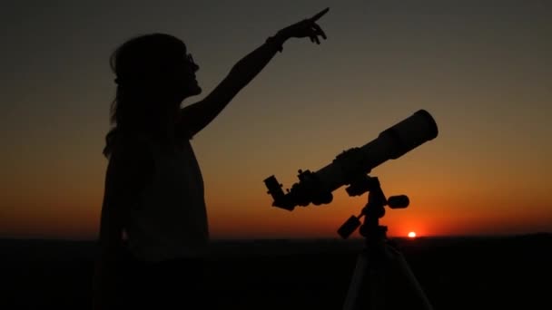 Młoda kobieta, patrząc przez teleskop astronomiczny w godzinach wieczornych. - Materiał filmowy, wideo