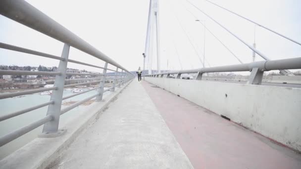 Young sportive man training jugging by bridge, urban workout. - Materiaali, video
