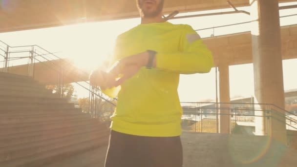Young sportive man training jugging by bridge, urban workout. - Video, Çekim