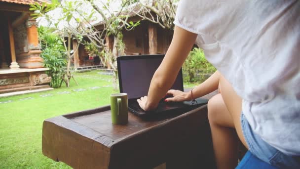 Mujer joven que trabaja usando el ordenador portátil en el patio
 - Metraje, vídeo