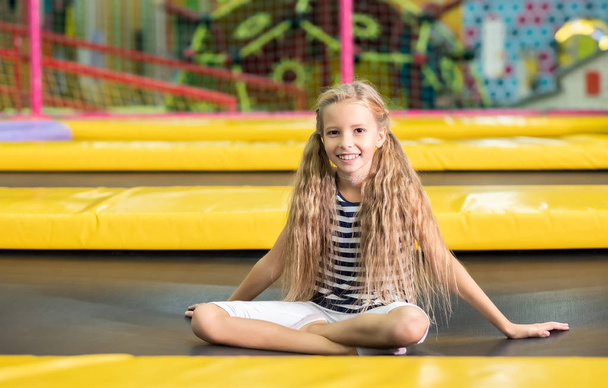 Little pretty smiling girl sitting on the trampoline - Фото, зображення