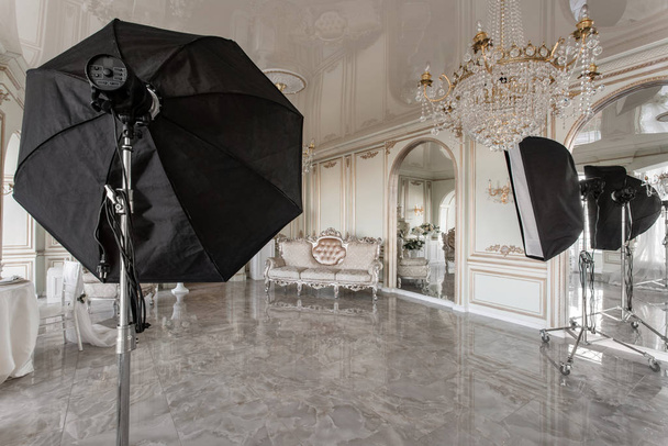 Innenraum eines Fotostudios. klassische luxuriöse Apartments mit weißem Kamin, Sofa, großen Fenstern und Kronleuchter. - Foto, Bild