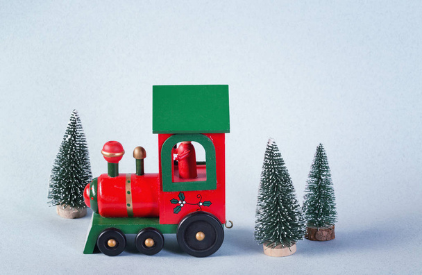 Tren de juguete de madera rodeado de árboles de Navidad
 - Foto, Imagen