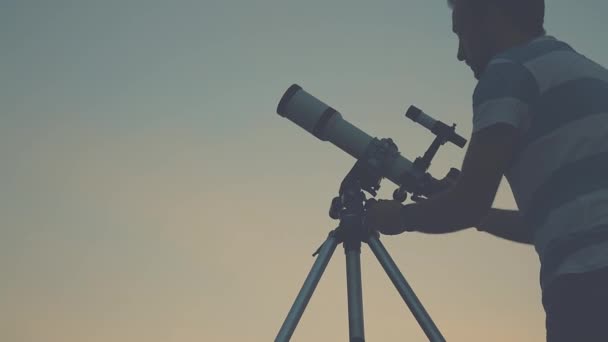 junger Mann richtet sich ein und schaut abends durch das astronomische Teleskop. - Filmmaterial, Video