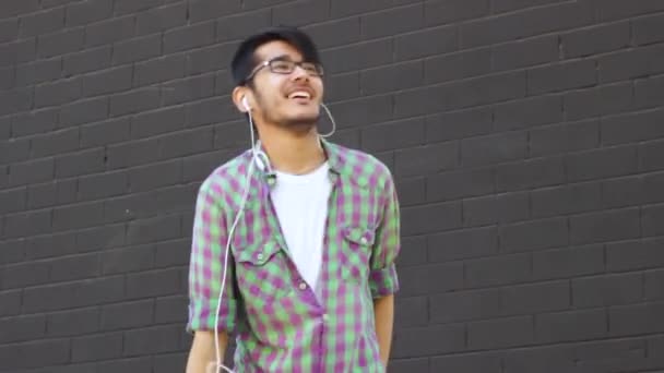 Aasialainen mies tanssii harmaata seinää vasten
 - Materiaali, video