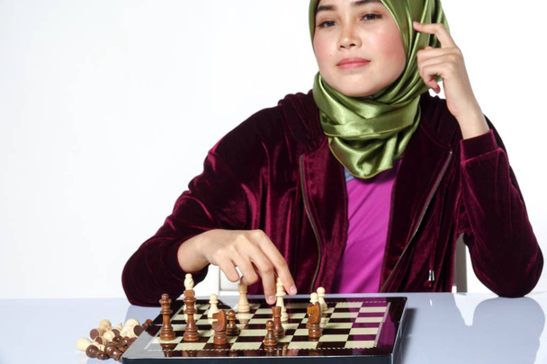 Portrait of a beautiful veiled young woman smiling playing a chess game - Photo, image