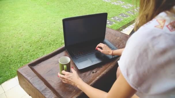 Young woman working using laptop in yard - Footage, Video
