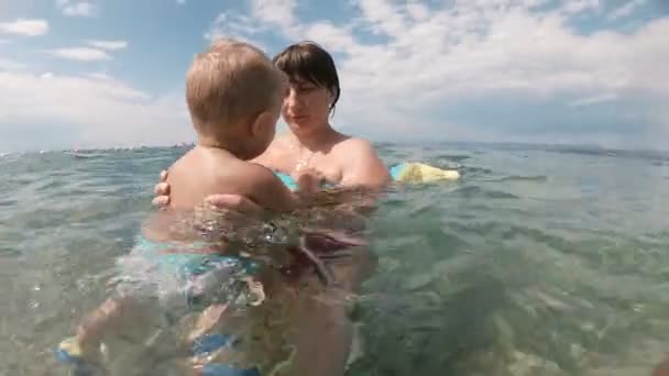 Young mother swimming and playing with male child boy in sea or ocean water sunny day outdoor on natural background. - Záběry, video