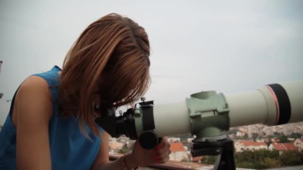 Молода жінка дивиться на міський пейзаж за допомогою телескопа
 - Кадри, відео
