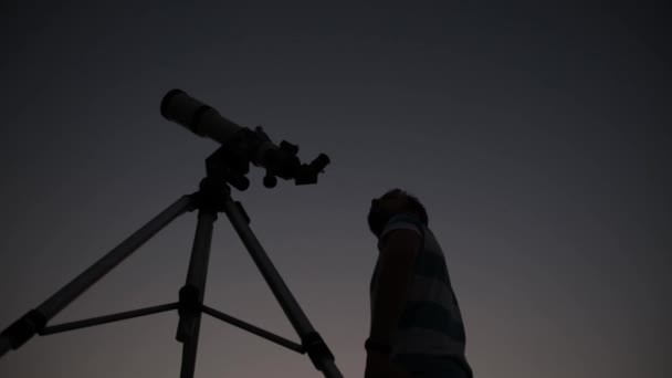 Muž v noci při pohledu na hvězdy dalekohledem. - Záběry, video