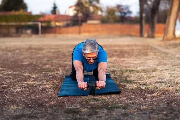 Idősebb ember, csinál egy edzés ab Roller szabadban - Fotó, kép