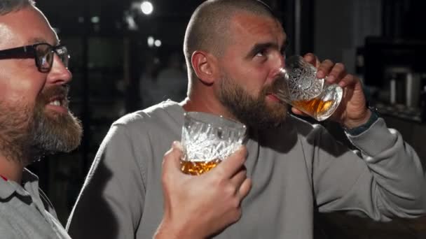 Pohledný muž a jeho přítel sledovat fotbalový zápas v whisky baru - Záběry, video