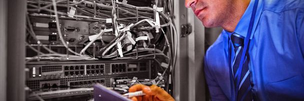 Technician maintaining record of rack mounted server on clipboard in server room - Fotoğraf, Görsel
