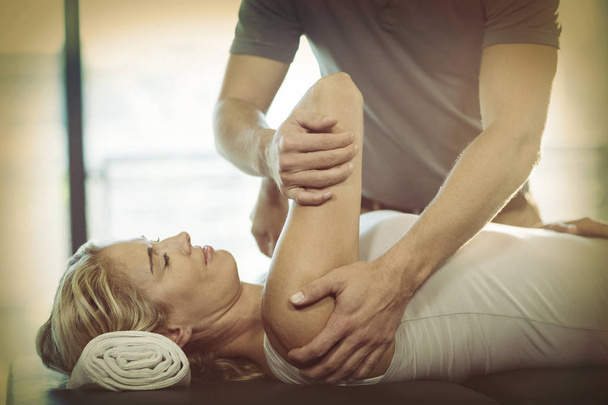 Woman receiving shoulder therapy from physiotherapist in clinic - Valokuva, kuva