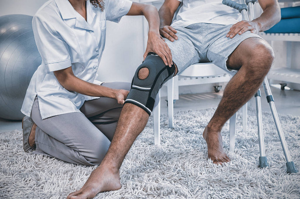Physiotherapist examining patients knee in clinic - Fotoğraf, Görsel
