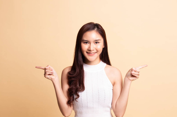 Young Asian woman point to left and right   on beige background - Photo, Image