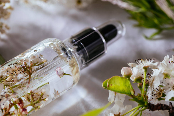 Esenciální olej, čerstvé bílé květy třešně, na pozadí zelených listů - Fotografie, Obrázek