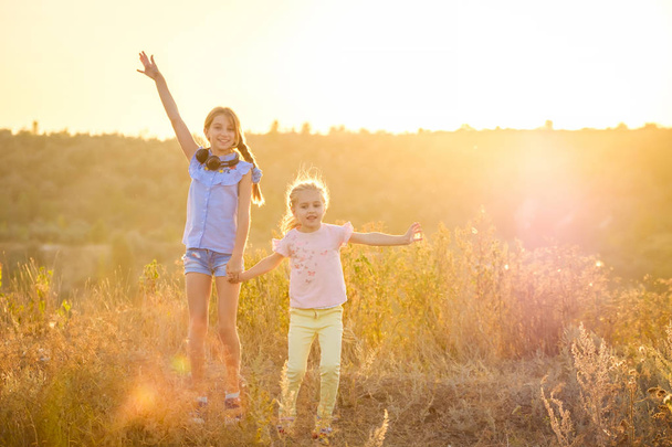 Маленькие улыбающиеся девочки стоят с радостными поднятыми руками
 - Фото, изображение
