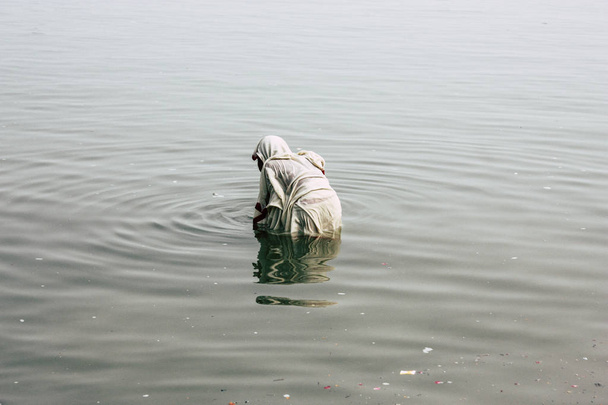 Varanasi India November 10, 2018 View of unknown old Indian woman praying in the Ganges river at Varanasi in the afternoon - Zdjęcie, obraz