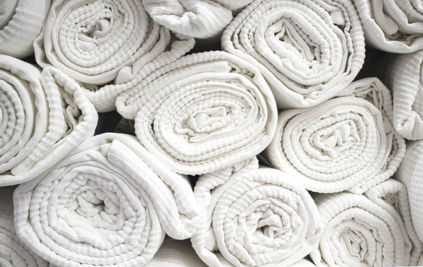 Loads of rolled white cotton bedspreads. Closeup - Photo, Image