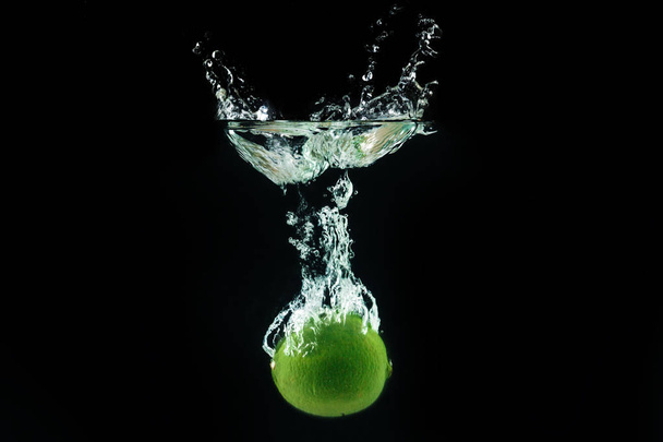 Fresh lime dropped into water with splash - Fotó, kép