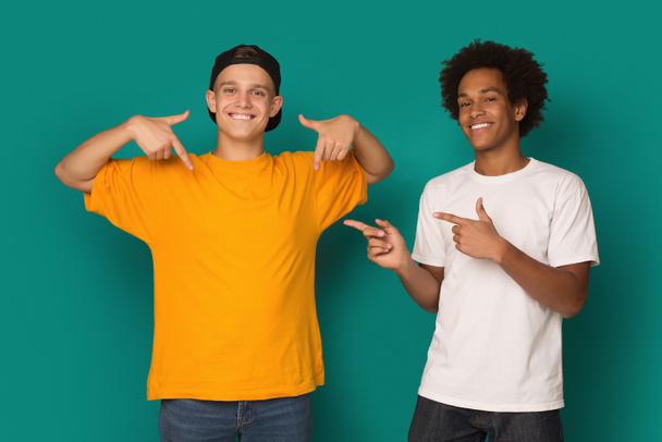 Diversos adolescentes apuntando a la camiseta en blanco sobre fondo azul, espacio de copia
 - Foto, imagen