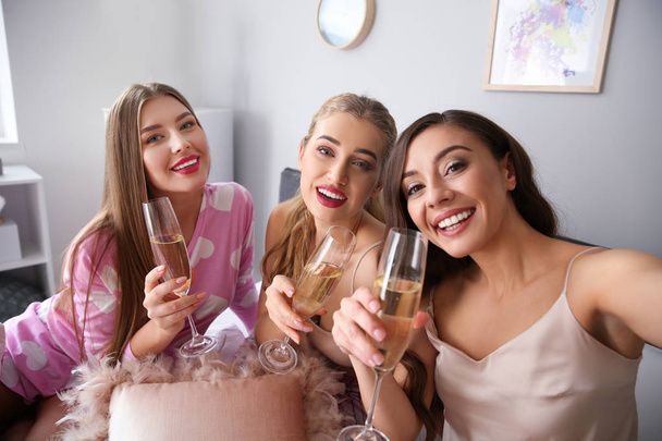 Hermosas mujeres jóvenes tomando selfie mientras bebe champán en el dormitorio
 - Foto, imagen