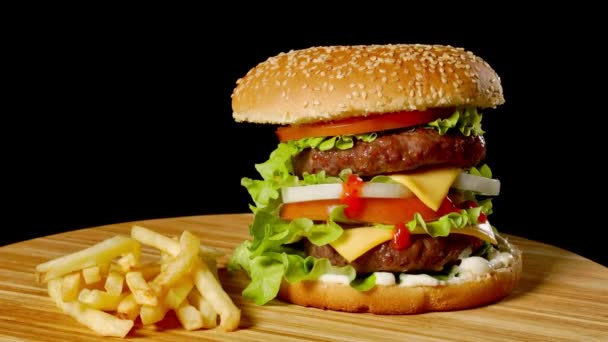 Kézműves marha burger és hasábburgonyával, elszigetelt fekete háttér mártással. gyorsétterem - Felvétel, videó