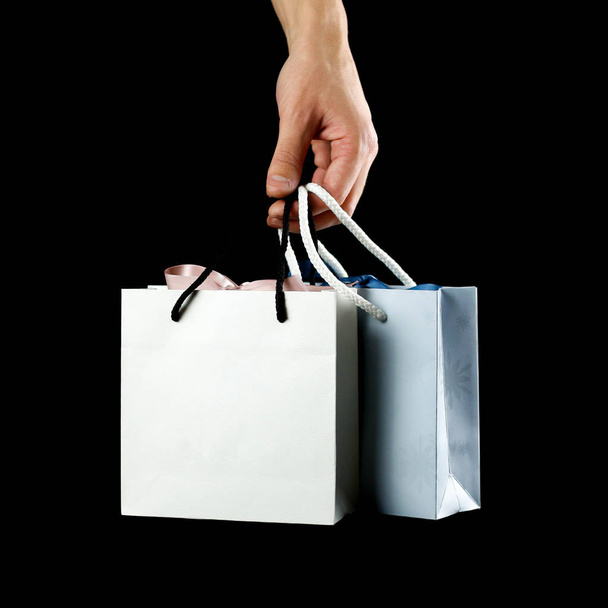 Hand holding a beautiful gift bag. Close up. Isolated on black background. - Foto, Imagen