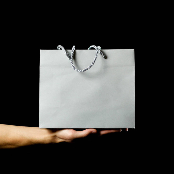 Hand holding a beautiful gift bag. Close up. Isolated on black background. - Fotografie, Obrázek