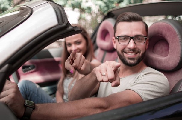 loving couple in a convertible car pointing at you - Foto, Bild