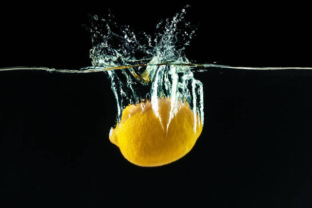 fresh yellow lemon in water splash on black background - Foto, Bild