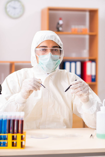 Joven bioquímico con traje protector trabajando en el laboratorio
 - Foto, imagen