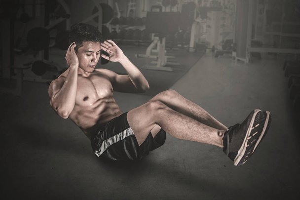Widok z boku mięśni człowieka robi ćwiczenia brzuszków na podłodze. Strzał w centrum fitness - Zdjęcie, obraz