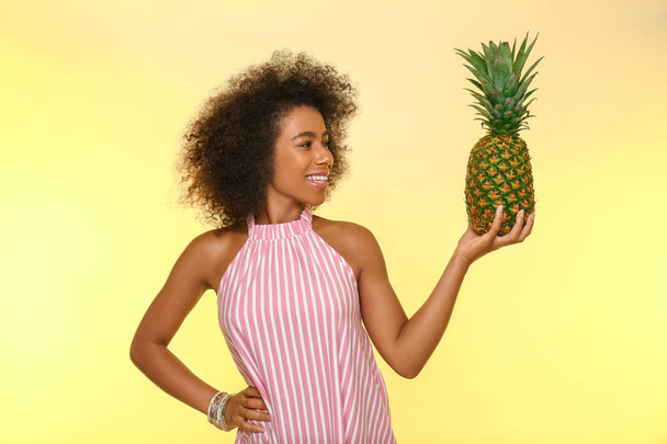 Прекрасна афро-американська жінка з ананасом на кольоровому фоні - Фото, зображення