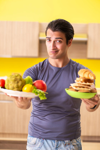 Uomo che ha una scelta difficile tra cibo sano e malsano - Foto, immagini