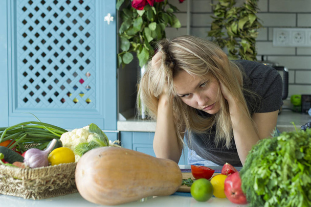das Mädchen ist müde in der Küche. Vegetarische Küche. ein junger Europäer in seinen Zwanzigern. Das Konzept der gesunden Ernährung. - Foto, Bild
