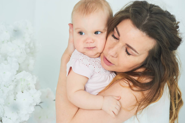 Gyönyörű fiatal anya baba lány karjaiban. A koncepció egy boldog család, anyaság. anya játszik gyermekével, a hálószobában. - Fotó, kép