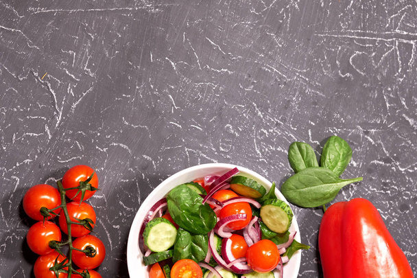 Salada de legumes em uma placa branca em um fundo cinza, ao lado do peppe búlgaro
 - Foto, Imagem