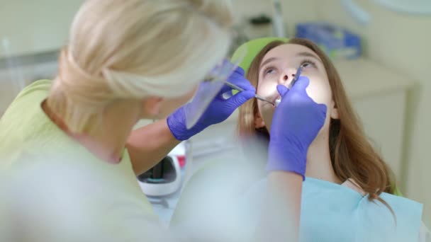 Patient mit Zahnschmerzen sitzt im Zahnarztstuhl. Zahnarzt arbeitet mit Mädchen - Filmmaterial, Video
