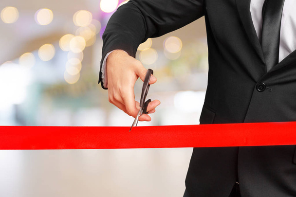Businessman cutting red ribbon with pair of scissors - Foto, Imagem