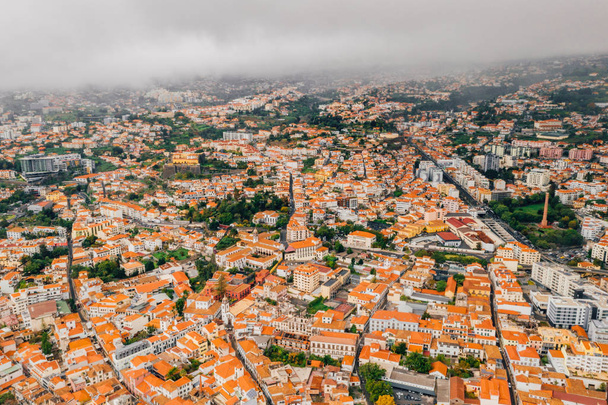 Aerial view of the Funchal old town - the capital of Madeira island during cloudy weather. Small houses with orange rooftops by the Atlantic ocean.  - Photo, image