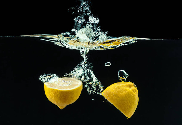 fresh yellow lemon in water splash on black background - 写真・画像