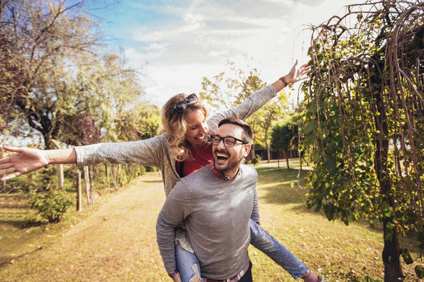 Couple ayant plaisir homme donnant piggyback à la femme dans le parc d'automne
 - Photo, image